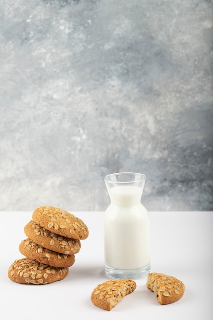 Multigrain cookies with fresh cool milk placed on blue tablecloth .