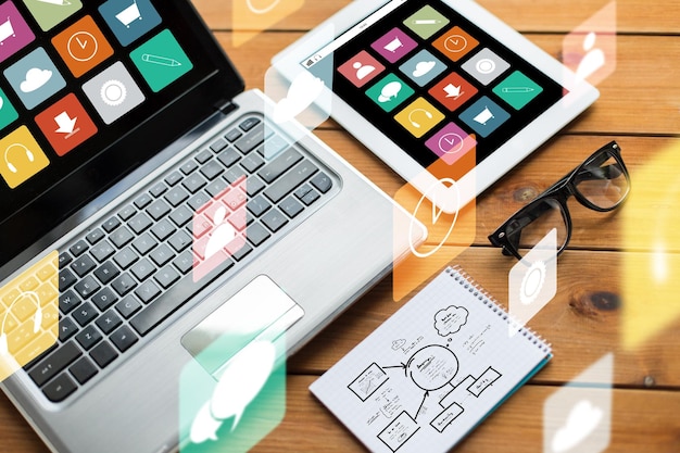 Фото Мультимедиа, отзывчивый дизайн и технологическая концепция - крупный план на ноутбуке, планшетном пк, ноутбуке и очках со схемой и значками меню на деревянном столе