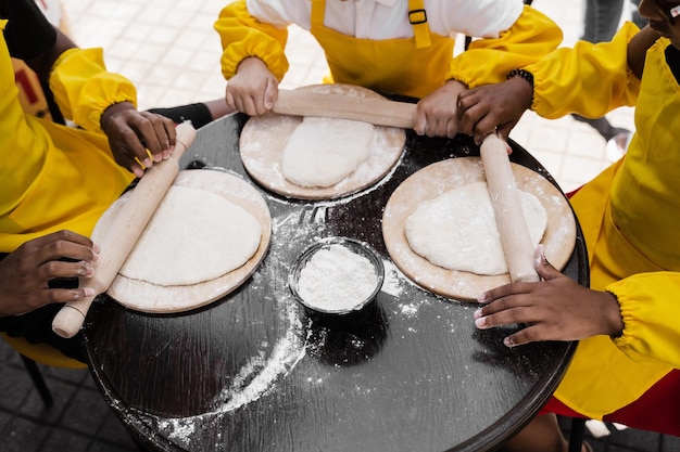 Multinationaal bedrijf van kinderen kookt deeg close-up Jonge koks kinderen koken khachapuri