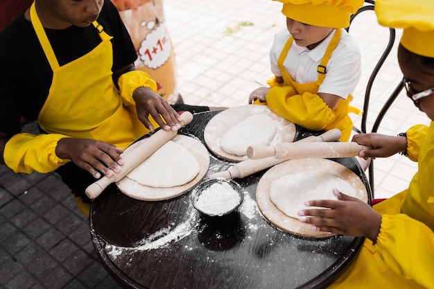 Multinationaal bedrijf van kinderen kookt deeg close-up Jonge koks kinderen koken khachapuri