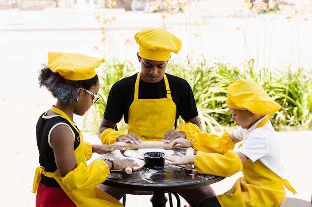 Multinationaal bedrijf van kinderen kookt in gele uniformen deeg koken voor bakkerij Afrikaanse tiener en zwart meisje veel plezier met blanke kindjongen en koken voedsel