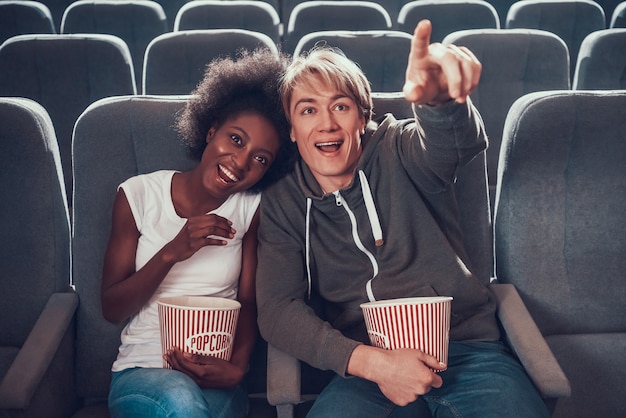 Multinational couple is watching comedy in cinema.