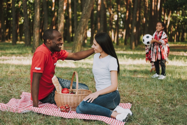 Multinationale paar zitten op tafellaken op picknick.