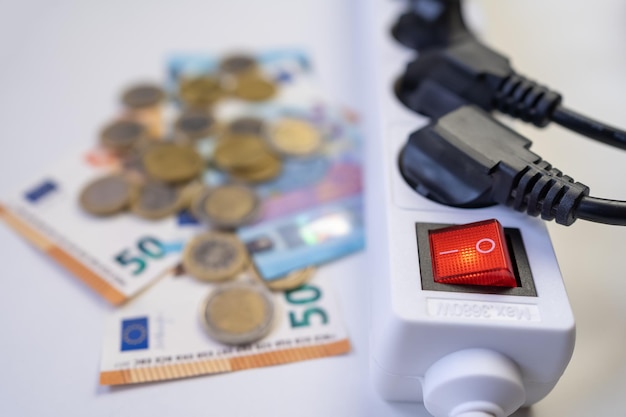 Multiple cables plugged into a power strip and money representing the high cost of electricity from inflation