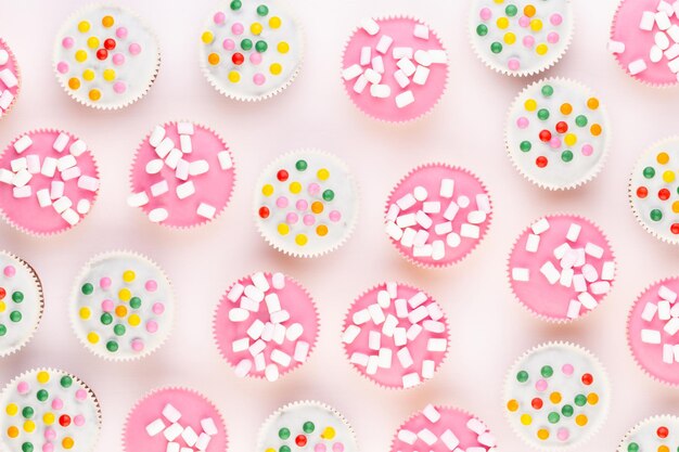 Multiple colorful nicely decorated muffins on a white background, top view.