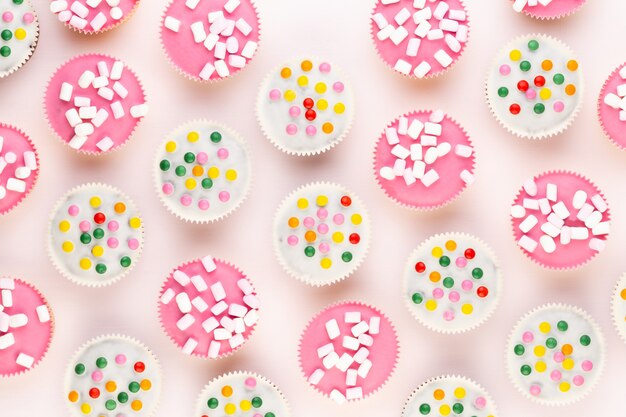 Multiple colorful nicely decorated muffins on a white background, top view.