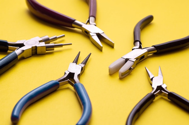 Multiple jewelry pliers on an isolated yellow background