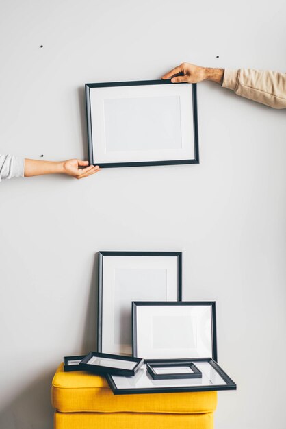 Photo multiple many black picture frames on white wall. woman hanging a frame on a wall.