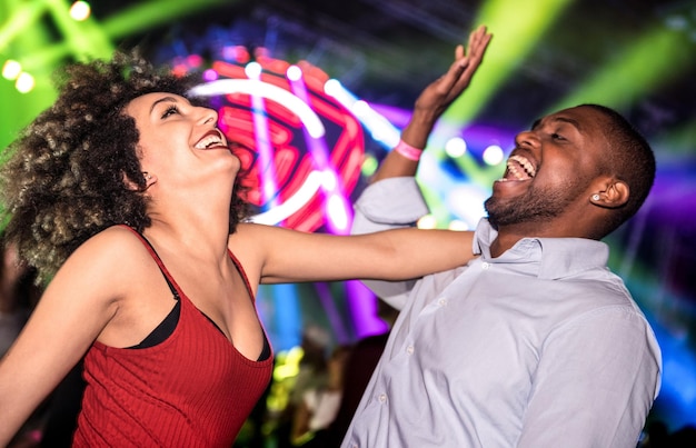 Multiraciaal jong koppel dansen in nachtclub met laserlichtshow