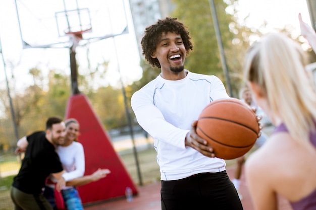 Multiraciaal paar speelbasketbal op openluchthof