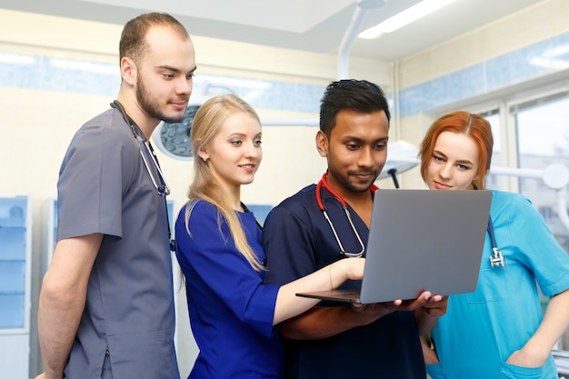 Multiraciaal team van jonge artsen die aan laptopcomputer in medisch bureau werken.