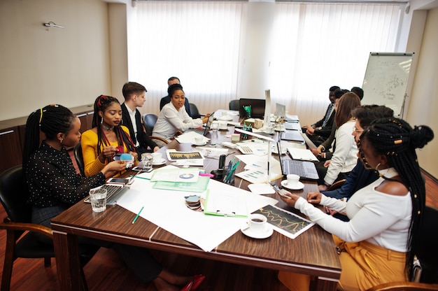 Photo multiracial business team addressing meeting around boardroom table.