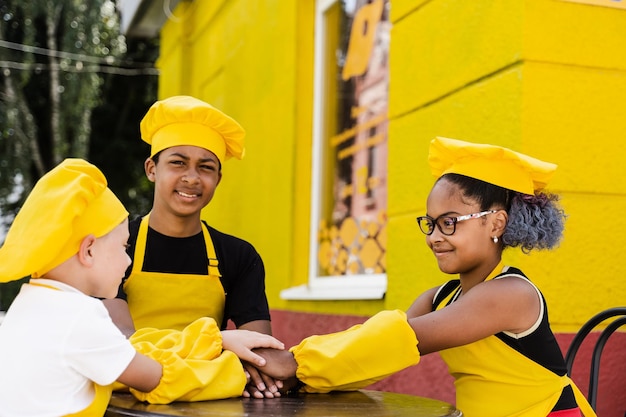 Multiracial children cook touching hands together forming pile Friendship of multinational kids Childhood cooks in chefs hat and yellow apron uniform put hands on each other