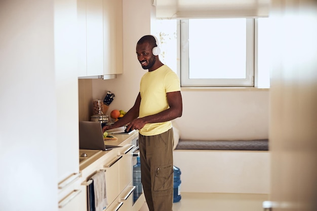 Multiracial cook watching a film on laptop while cooking