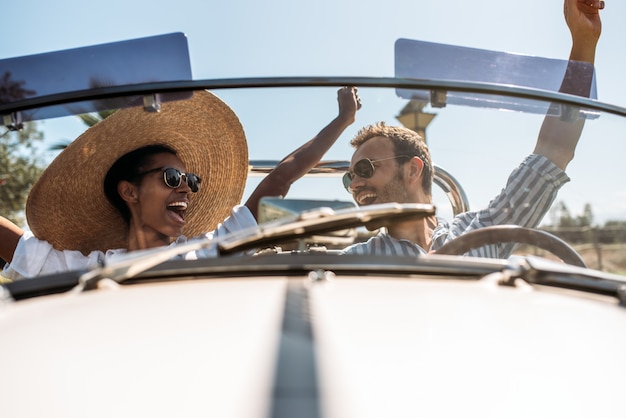 Multiracial couple in a convertible vintage car