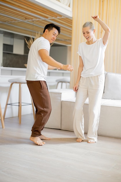 Multiracial couple dancing while resting at home