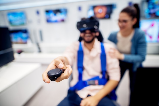 Multiracial couple having fun with VR goggles while boy sitting in the chair in the tech store. Customer's service. Shopping time.