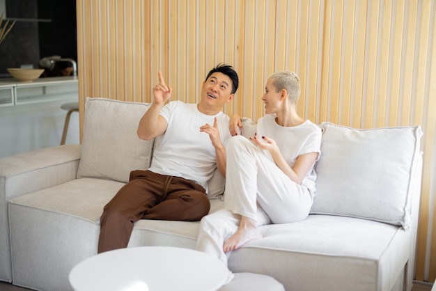 Multiracial couple sit and talk on sofa at home