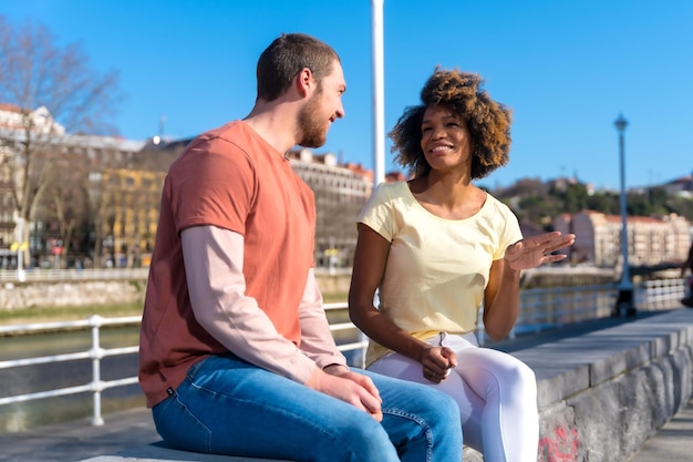 Multiracial couple on the streets of the city lifestyle sitting talking on the weekend