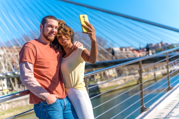 Coppia multirazziale attraverso il selfie stile di vita delle strade della città sorridente vicino al fiume in vacanza