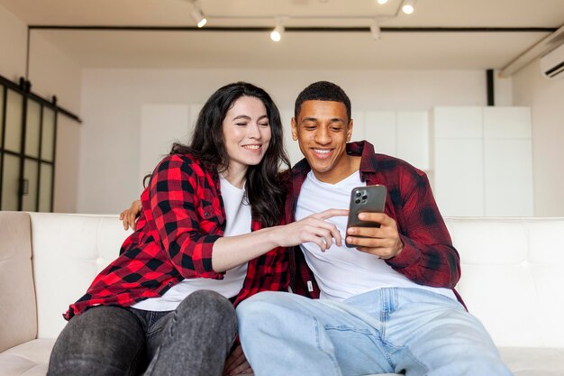 Photo multiracial couple using smartphone at home on comfortable sofa african american man with woman