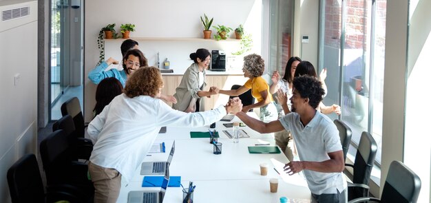 Multiracial coworkers shake hands and hug to celebrate business great success Horizontal banner