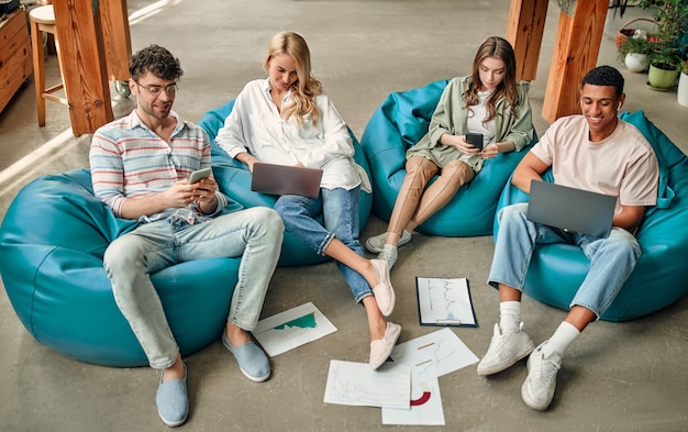 Multiracial creative people in modern office. Group of young business people are working together with laptop, tablet, smart phone, notebook, graphs. Successful team in coworking. Freelancers