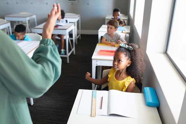 Photo multiracial elementary school students looking at caucasian young female teacher during class