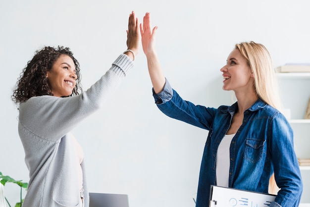 Photo multiracial employees giving high five at office