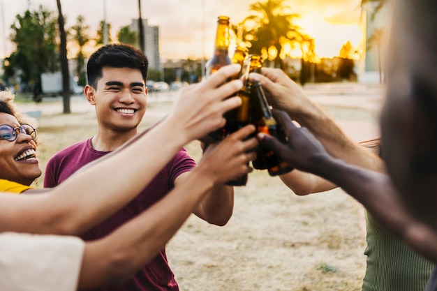 Multiracial friends celebrating and toasting beers at beach party