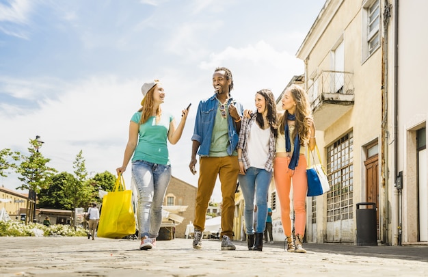 Gli amici multirazziali raggruppano divertiresi insieme camminando sulla via della città