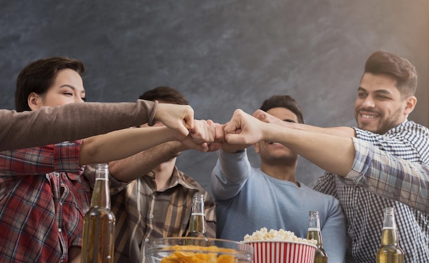 Multiracial friends join fists while having party at home