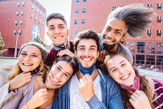 Amici multirazziali che prendono selfie con la maschera facciale aperta al campus universitario