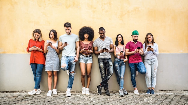 Multiracial friends using smartphone against wall