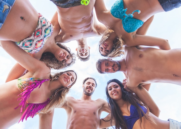 Multiracial group of friends embraced at seaside.