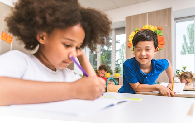 Foto gruppo multirazziale di bambini della scuola primaria - scolari giocosi che si godono l'orario scolastico e le lezioni con l'insegnante e i compagni di classe