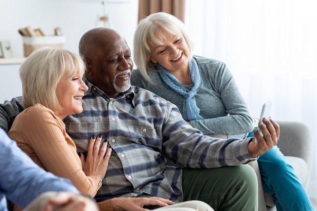 Photo multiracial group of pensioners using mobile phone