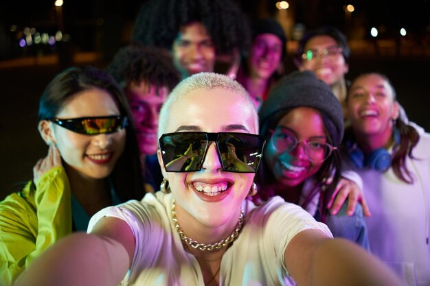 Photo multiracial group of people taking a selfie in a disco party happy friends having fun together in a