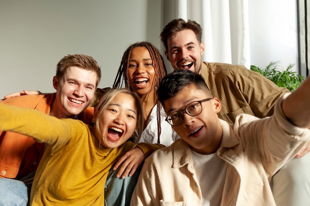 multiracial group of young friends smiling and taking selfies for the camera