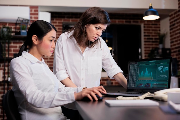 Multiracial marketing company employees in office workspace analyzing financial charts and graphs. Executive board members reviewing wrongly issued accounting data on laptop screen.