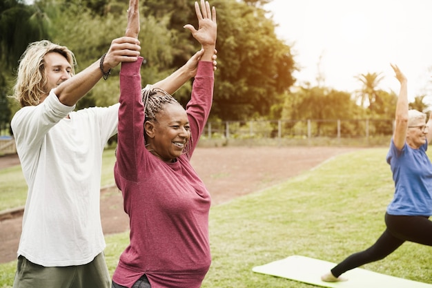 Persone multirazziali che fanno lezione di yoga all'aperto nel parco cittadino