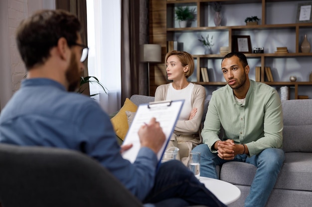 Multiracial quarrel between husband and wife at a session with a psychotherapist A visit to a family psychologist for a married couple A doctor consults an unhappy married couple Help psychologist