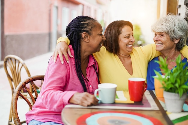 Multiracial senior friends haing fun outdoor at bar restaurant Focus on center woman face