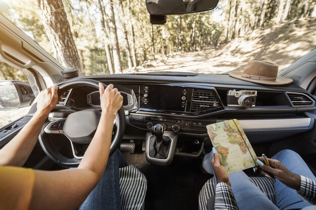 Donne anziane multirazziali che si divertono sulla strada in camper - focus sulle mani della donna che tengono la ruota