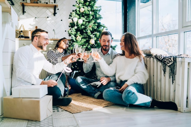 multiracial smiling young men and women clinking glasses during Christmas holidays