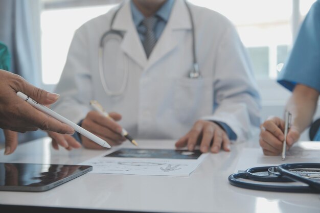 Multiracial team of doctors discussing a patient standing grouped in the foyer looking at a tablet computer close up view