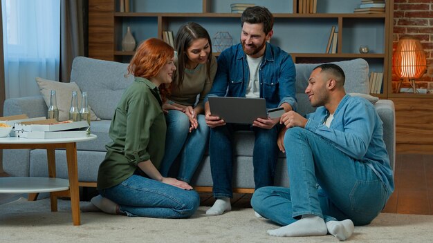 Multiracial team friends ethnicity diversity shoppers sit in living room work with laptop use credit