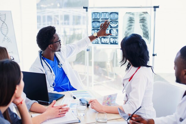 Squadra multirazziale di giovani medici che discutono della tomografia computerizzata in clinica