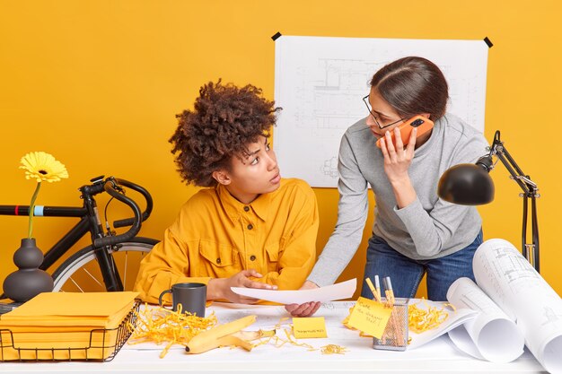 Foto le donne architetto multirazziali discutono del futuro progetto di ingegneria, le scartoffie posano al deskstop creano progetti?