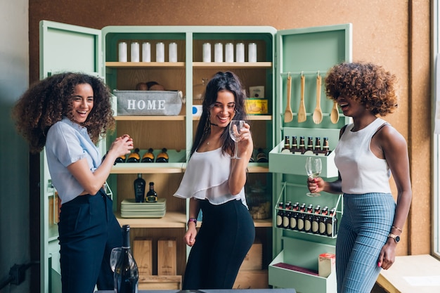 multiracial women celebrating and dancing in modern pub 